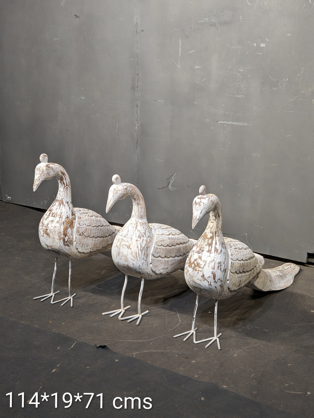 Three decorative stone ducks on a dark surface with a gray background