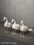 Three decorative stone ducks on a dark surface with a gray background