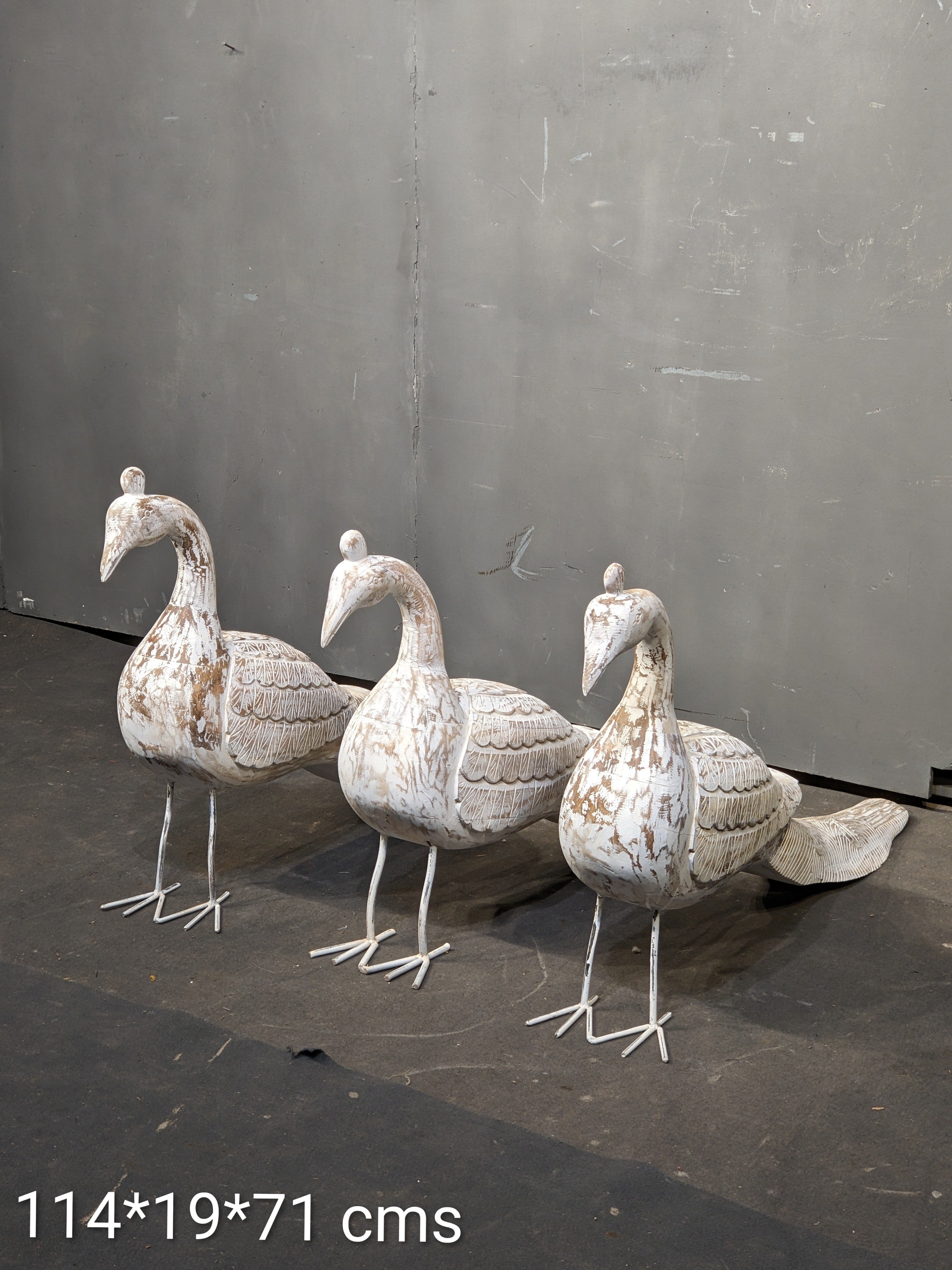 Three decorative stone ducks on a dark surface with a gray background