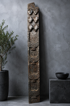 Antique Naga tribal totem panel with six carved mask faces against a grey concrete wall